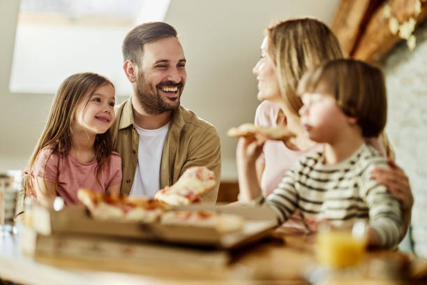 istock Young happy family talking while eating pizza for lunch at home. 1677685713