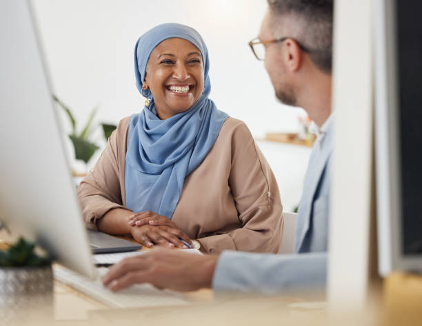 istock Smile, teamwork and business people in office for training, advice or collaboration while working on computer. Smile, help and Muslim senior woman mentor laugh with colleague while brainstorming idea 1677689695