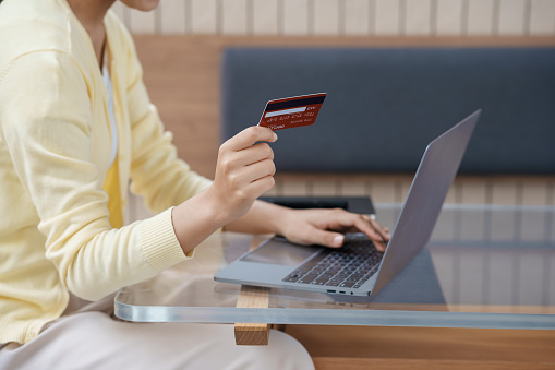 Close-up of woman using laptop and credit card for online shopping. Online payment.