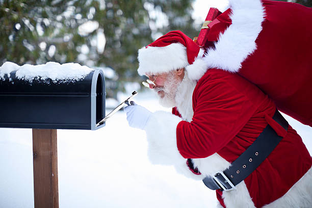 Cheerful Santa Claus Peeking in Mailbox with Christmas Gifts stock photo