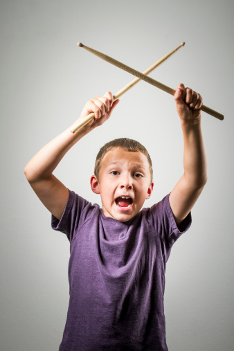 A young drummer with his sticks above his head. Vignette is intentional