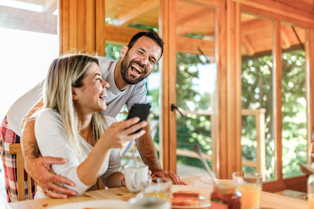 istock Cheerful couple using mobile phone during breakfast in the morning. 1677724620