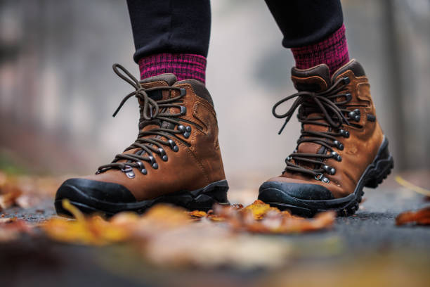 Hiking boot on road with autumn leaves. Waterproof leather ankle boots
