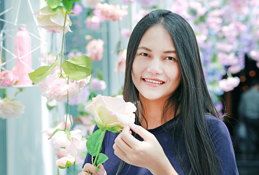 Beautiful young Asian woman posing near pink flowers in a garden.