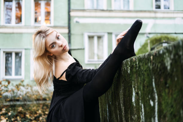 ballerine dansant dans la rue de la ville d’automne, danseuse de ballet moderne en robe noire, chaussures de pointe à l’extérieur. étirements de ballerines, routine quotidienne d’étirement de ballet - flying contemporary dancing dancer photos et images de collection