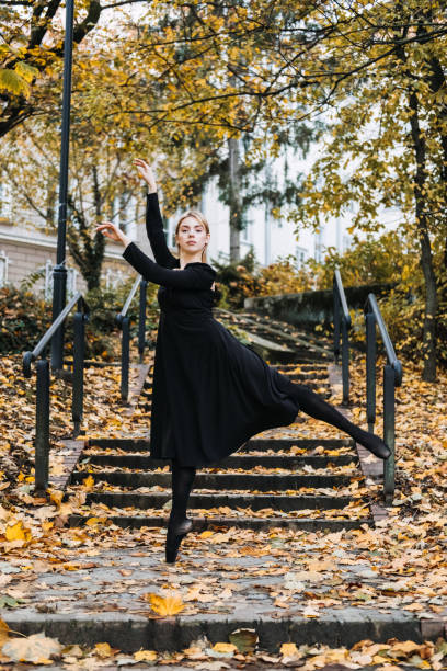 ballerine dansant dans la rue de la ville d’automne, danseuse de ballet moderne en robe noire, chaussures de pointe à l’extérieur. étirements de ballerines, routine quotidienne d’étirement de ballet - flying contemporary dancing dancer photos et images de collection