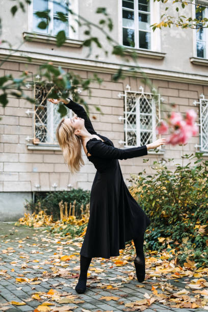 ballerine dansant dans la rue de la ville d’automne, danseuse de ballet moderne en robe noire, chaussures de pointe à l’extérieur. étirements de ballerines, routine quotidienne d’étirement de ballet - flying contemporary dancing dancer photos et images de collection