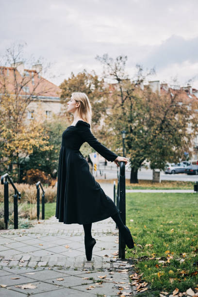 ballerine dansant dans la rue de la ville d’automne, danseuse de ballet moderne en robe noire, chaussures de pointe à l’extérieur. étirements de ballerines, routine quotidienne d’étirement de ballet - flying contemporary dancing dancer photos et images de collection