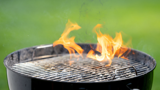 Burning wood in barbeque grill, preparing hot coals for grilling meat in the back yard. Shallow depth of field