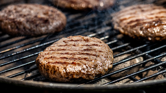 Close-up of burgers roasting on barbecue grill.