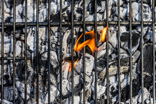 Overhead view of hot coals burning on barbecue grill.