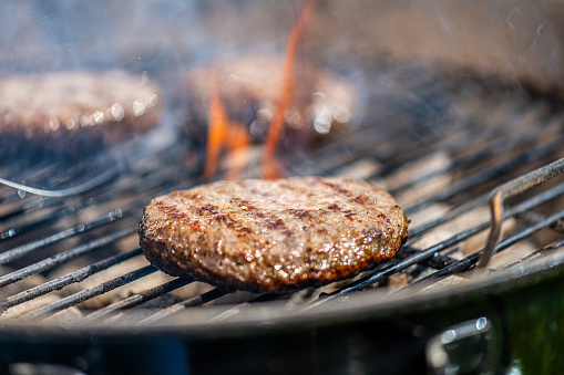 Close-up of burger roasting on barbecue grill.