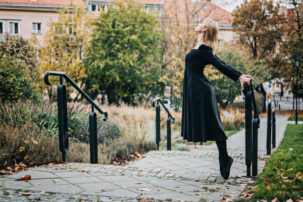 ballerine dansant dans la rue de la ville d’automne, danseuse de ballet moderne en robe noire, chaussures de pointe à l’extérieur. étirements de ballerines, routine quotidienne d’étirement de ballet - flying contemporary dancing dancer photos et images de collection