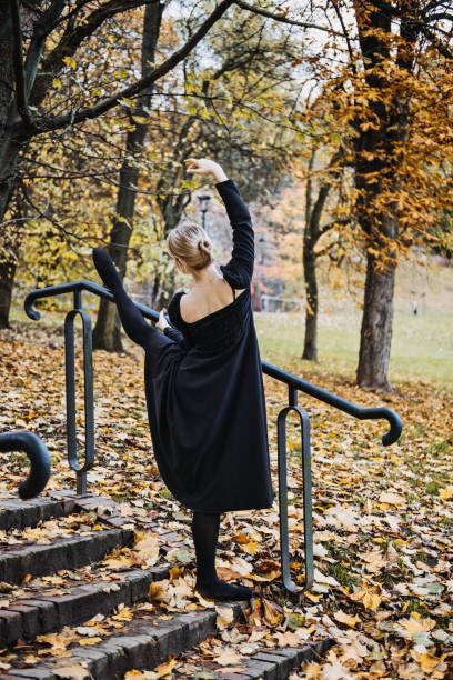 ballerine dansant dans la rue de la ville d’automne, danseuse de ballet moderne en robe noire, chaussures de pointe à l’extérieur. étirements de ballerines, routine quotidienne d’étirement de ballet - flying contemporary dancing dancer photos et images de collection