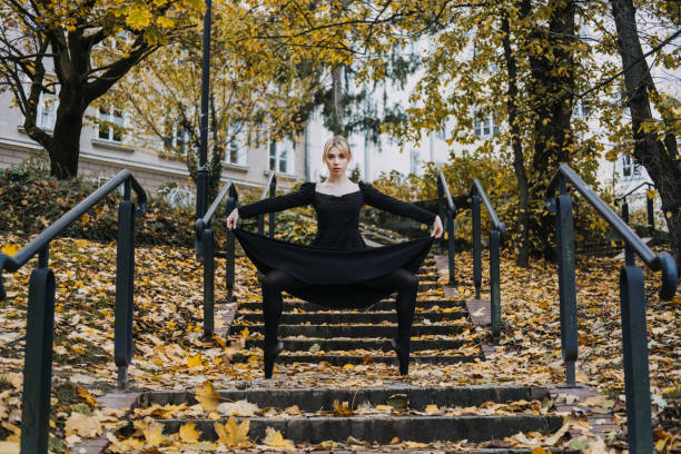 ballerine dansant dans la rue de la ville d’automne, danseuse de ballet moderne en robe noire, chaussures de pointe à l’extérieur. étirements de ballerines, routine quotidienne d’étirement de ballet - flying contemporary dancing dancer photos et images de collection