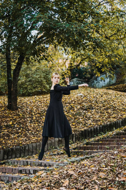 ballerine dansant dans la rue de la ville d’automne, danseuse de ballet moderne en robe noire, chaussures de pointe à l’extérieur. étirements de ballerines, routine quotidienne d’étirement de ballet - flying contemporary dancing dancer photos et images de collection