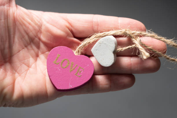 istock wooden white and pink heart held in hand 1677769681