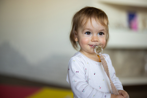 Happy little girl whit pacifier at home