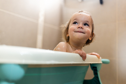 Portrait of little happy girl taking a bath in the bathroom