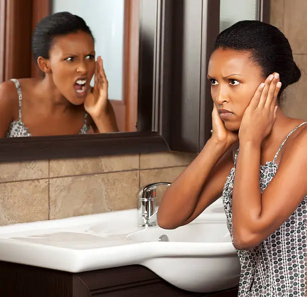 Close up portrait of black young woman yelling at herself in the bath mirror.