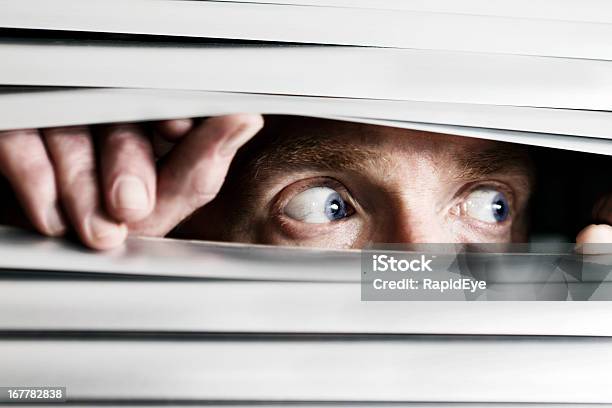 Fearful Man Looking Sideways Through Venetian Blind Stock Photo - Download Image Now