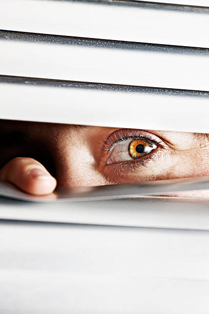 istock Panic-stricken woman peeps through closed venetian blinds 167782907
