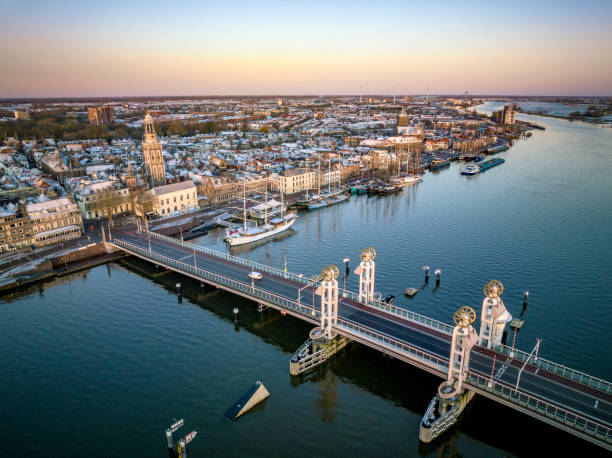 Kampen city bridge (Stadsburg) panoramic view at the river IJssel during a cold winter sunrise at the start of a cold bright winter day with light snow on the roofs. Kampen is an ancient Hanseatic League city at the shore of the river IJssel in Overijssel, The Netherlands.