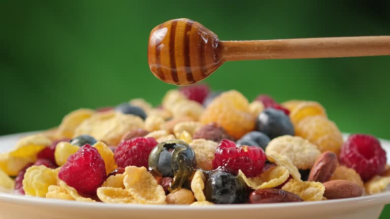 Pouring honey on oatmeal porridge. Healthy breakfast food