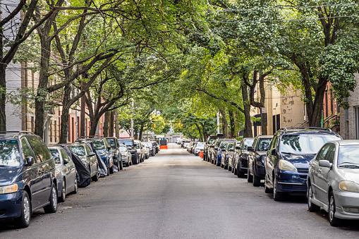 45th Road, Long Island City, Queens, New York, USA - August 23th 2023:   View down a treelined street with parked cars in both sides in a residential district