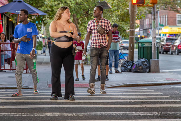 junge frau in einem sommerkleid wartet darauf, die straße zu überqueren - queens head stock-fotos und bilder