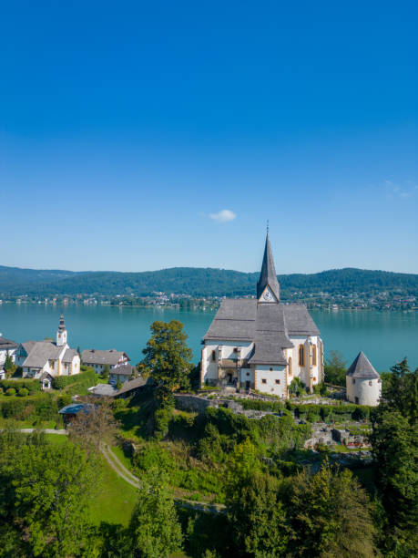 Maria Wörth at the Lake Wörthersee, Carinthia. Famous touristic location in the South of Austria. Maria Wörth at the Lake Wörthersee, Carinthia. Aerial view of the church and the famous touristic location in the South of Austria. maria woerth stock pictures, royalty-free photos & images