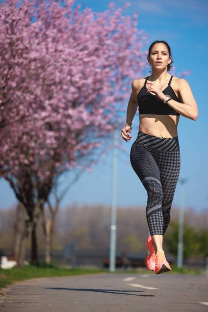 istock Active woman mid-air on the lane by the cherry tree tree line 1677939387