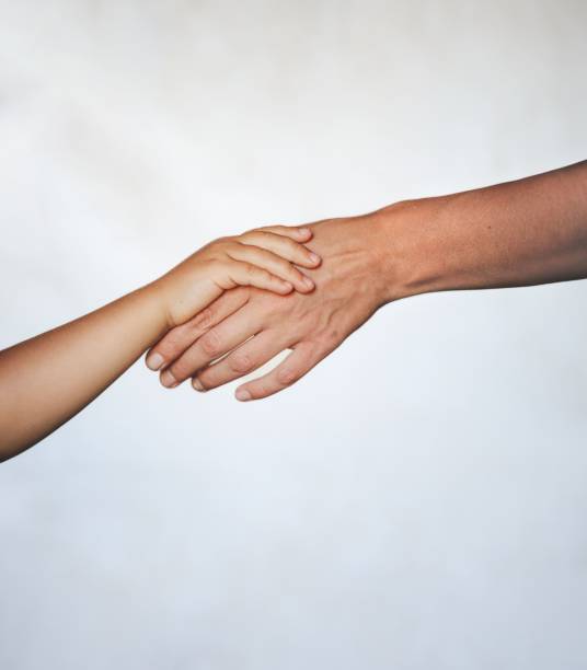 istock Young child holding their mother's hand against a white background. 1677953549