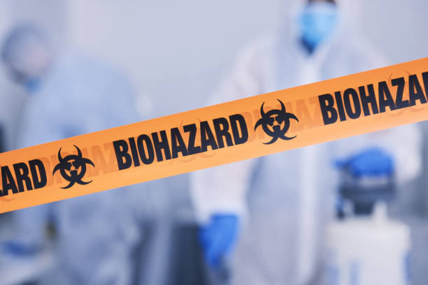 biohazard, tape and people with caution working with toxic, biology or team disinfect dangerous bacteria for health crisis. hazard, protection and warning for bio safety or cleaning in hazmat suit - bio hazard imagens e fotografias de stock