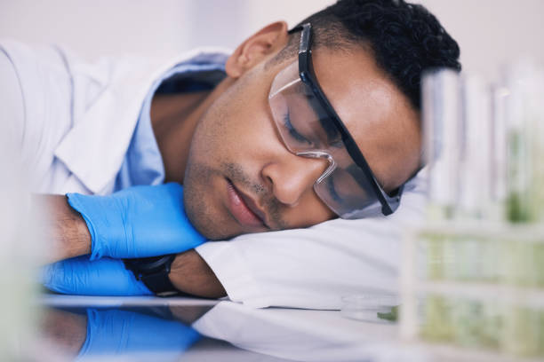 cientista, homem dormindo e cansado em laboratório para pesquisa de plantas, medicina e estudo farmacêutico à mesa. pessoa médica ou científica com sonho de carreira, fadiga e depressão por tubo de ensaio verde - healthcare and medicine digital tablet medical exam doctor - fotografias e filmes do acervo