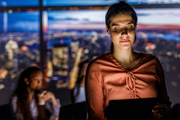 istock Woman using digital tablet that is illuminating her face 1677977161
