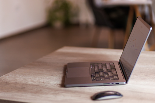 Close up shot of an open laptop on a desk, with a graph on the screen. Part of a series.