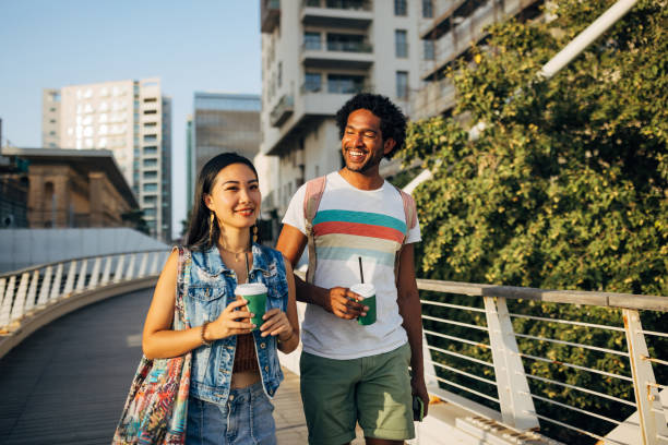 istock Smiling multiracial man walking with his Taiwanese friend, casually chatting with her, drinking takeaway coffee 1678021464