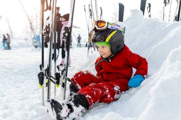 Cute adorable little kid boy enjoy having fun sledging down hill of snow heap snowdrift at alpine mountain skiing resort on bright winter day. Toddler beginner skier rest of training in ski school. lindo y adorable niño disfruta divirtiéndose en trineo cuesta abajo de nieve montones de nieve en la estación de esquí alpino de montaña en un brillante día de invierno. esquiador principiante descanso de entrenamiento en la escuela de esquí