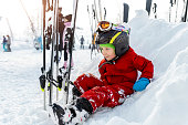 Cute adorable little kid boy enjoy having fun sledging down hill of snow heap snowdrift at alpine mountain skiing resort on bright winter day. Toddler beginner skier rest of training in ski school