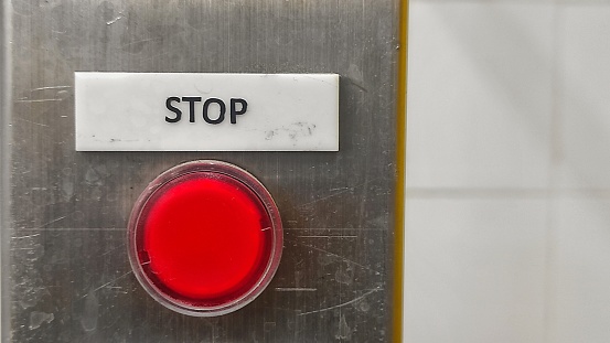 Red button and stop sign on the control panel indicate the the button to stop the machine in production room of factory