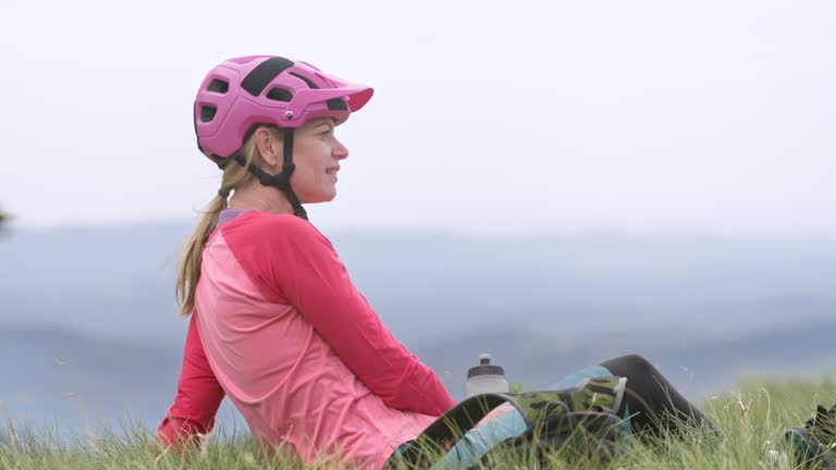 SLO MO Two women sitting in the grass and talking while having a break on their mountain biking trip