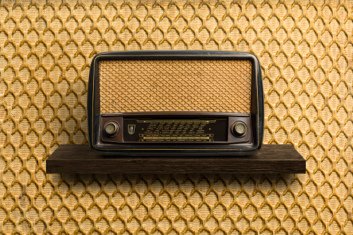 Antique radio on wooden shelf with vintage background.