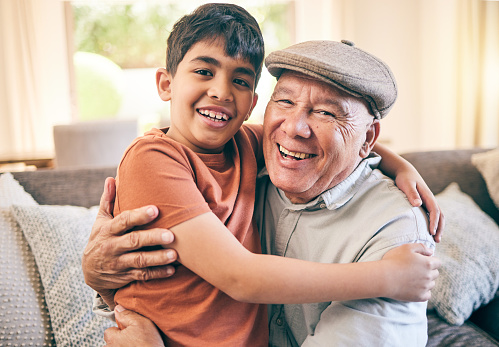 Happy, hug and portrait of child with his grandfather on a sofa in the living room for relaxing and bonding. Smile, love and senior man sitting and embracing a boy kid in the lounge of family home.