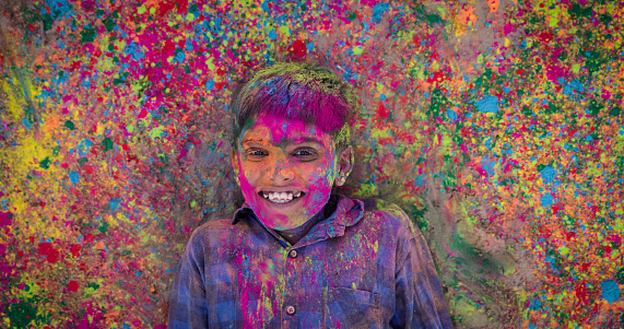 Happy Gypsy Indian children playing happy holi on sand dunes in desert village, Thar Desert, Rajasthan, India. Color powders are on their faces and clothes. Holi is a religious festival in India, celebrated, with the color powders, during the spring.