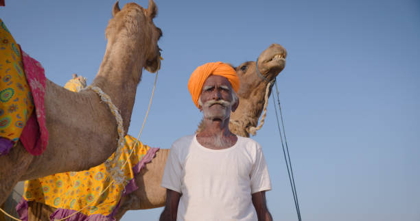 istock Indian man posing with camels on sand dunes, Rajasthan, India 1678105314