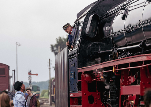 Beekbergen, the Netherlands - August 6th 2023: Engineers of a classic steam train chatting before the start of a journey.