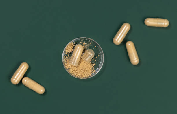 istock One capsule Opened in a jar on dark green. Taking dietary supplements with capsules 1678156808