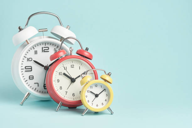 istock Three alarm clocks of different colors and sizes on a blue background. 1678158968