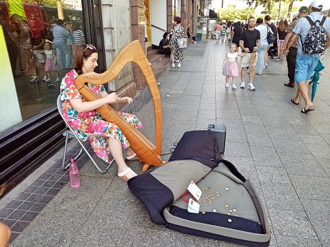 9th September 2023, Dublin, Ireland.  Woman busker playing the harp on O'Connell Street, Dublin city centre.